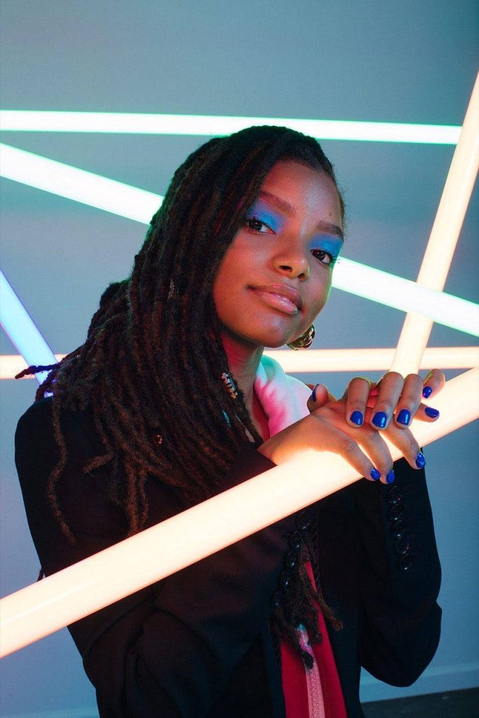 Halle Bailey portrait with dreadlocks blue eyeshadow neon tubes vibrant modern wallpaper background