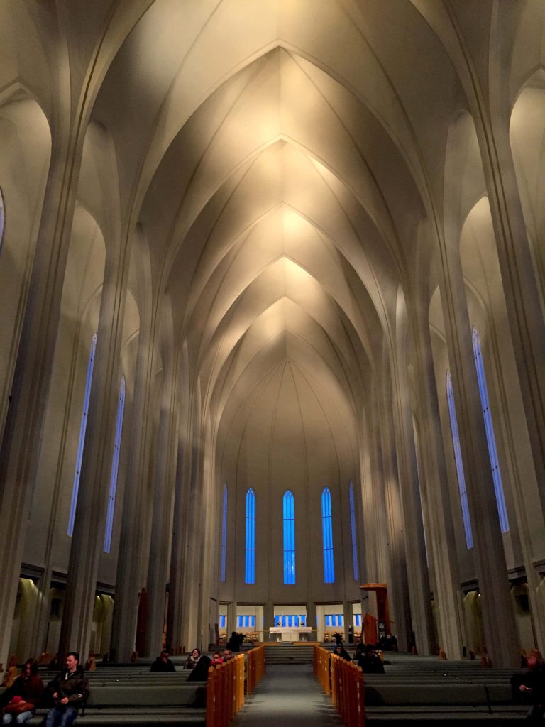 Interior view of Hallgrímskirkja church in Reykjavík with white arches and wooden pews Wallpaper