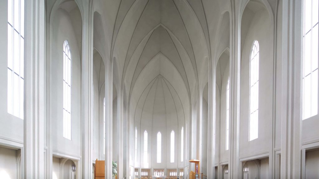 Hallgrímskirkja interior with towering white columns arched vaults and natural light streaming through windows Wallpaper