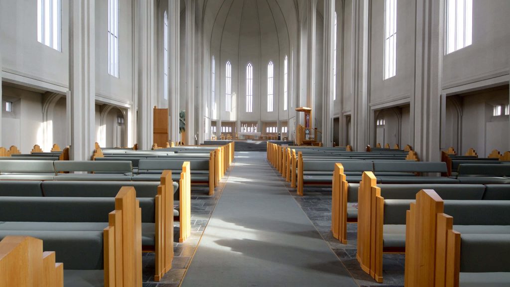 Symmetrical interior of Hallgrímskirkja minimal nave with tall columns and wooden pews wallpaper