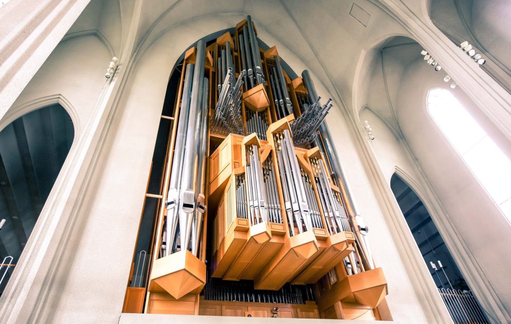 Low-angle view of Hallgrímskirkja pipe organ with silver pipes and light wood casing interior Wallpaper