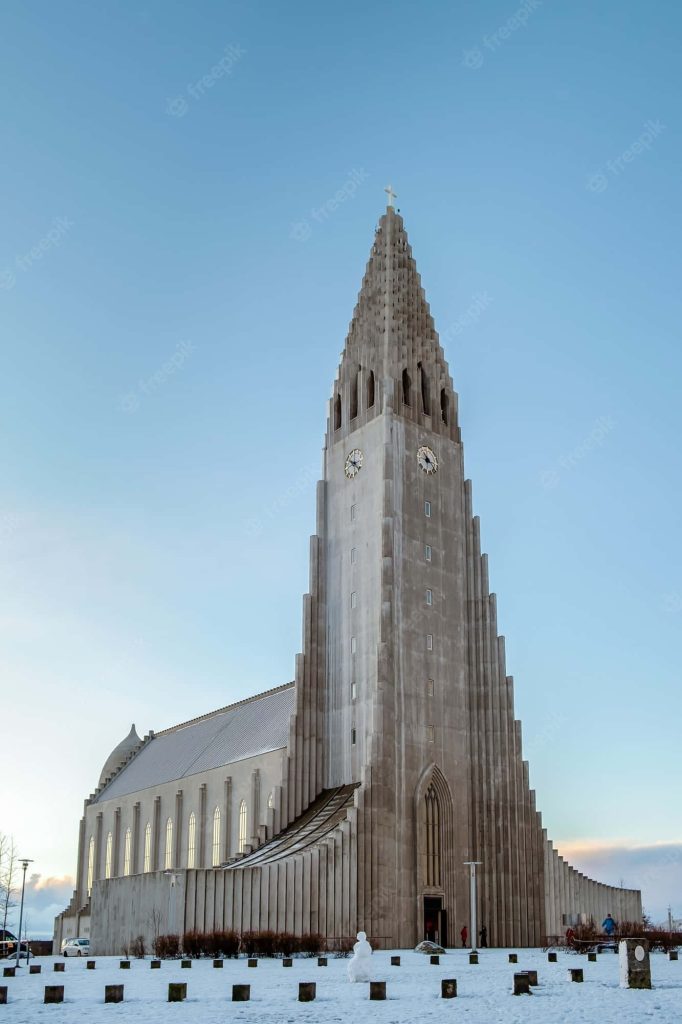 Hallgrimskirkja church tower in Reykjavik Iceland stands tall above snowy landscape blue sky Wallpaper