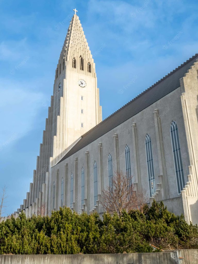 Side view of Hallgrímskirkja church with expressionist tower and arched windows in daylight Wallpaper