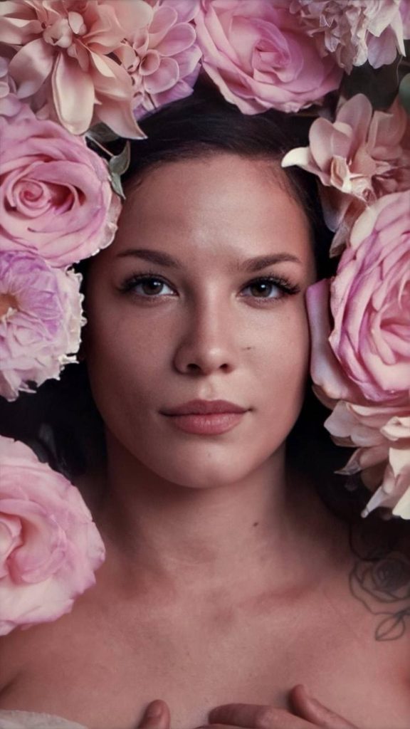 Close-up portrait of Halsey framed by blooming pink roses with soft lighting wallpaper