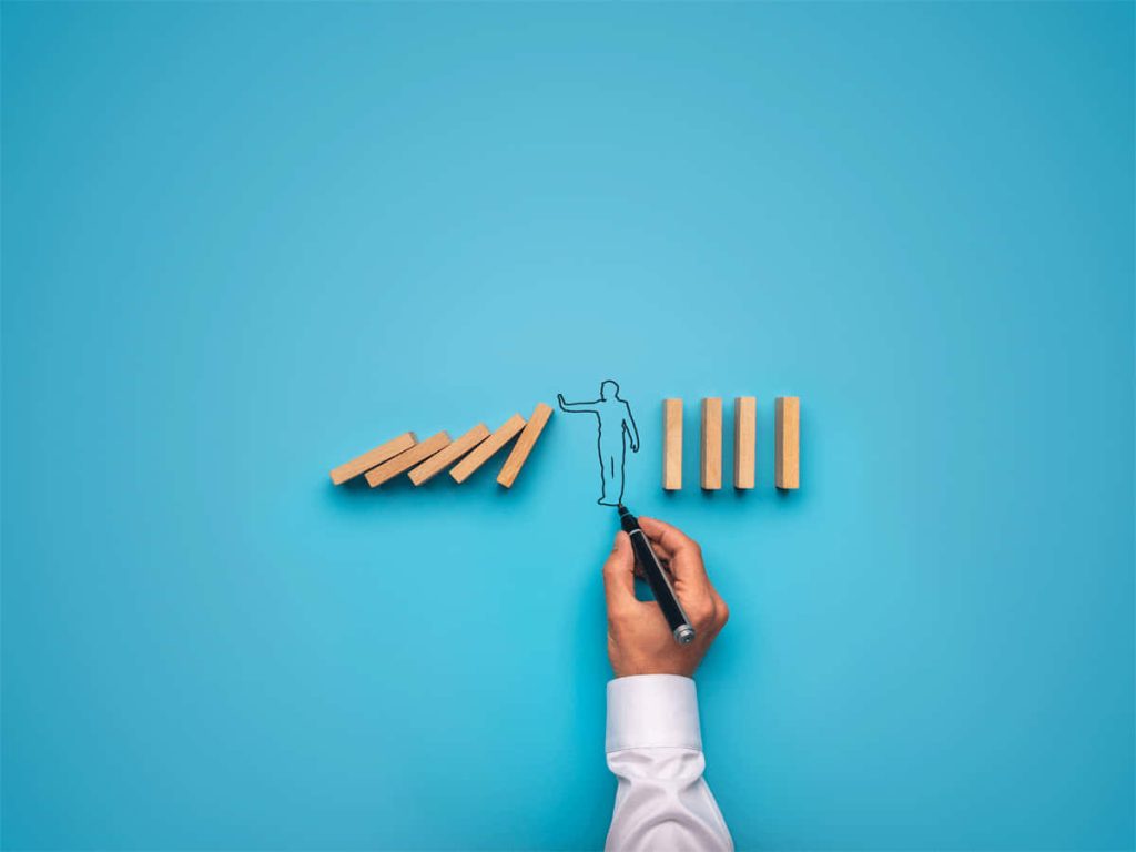 Hand drawing stick figure between falling and upright dominoes symbolizing leadership stability Wallpaper