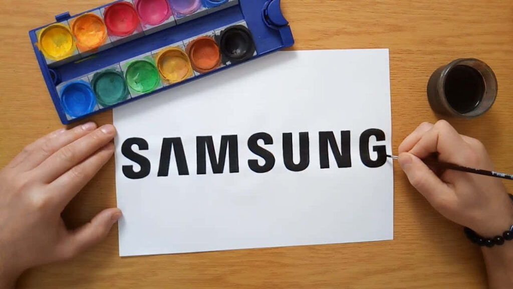 Hand-Painted Samsung Logo Art with Watercolors on Wooden Desk Wallpaper