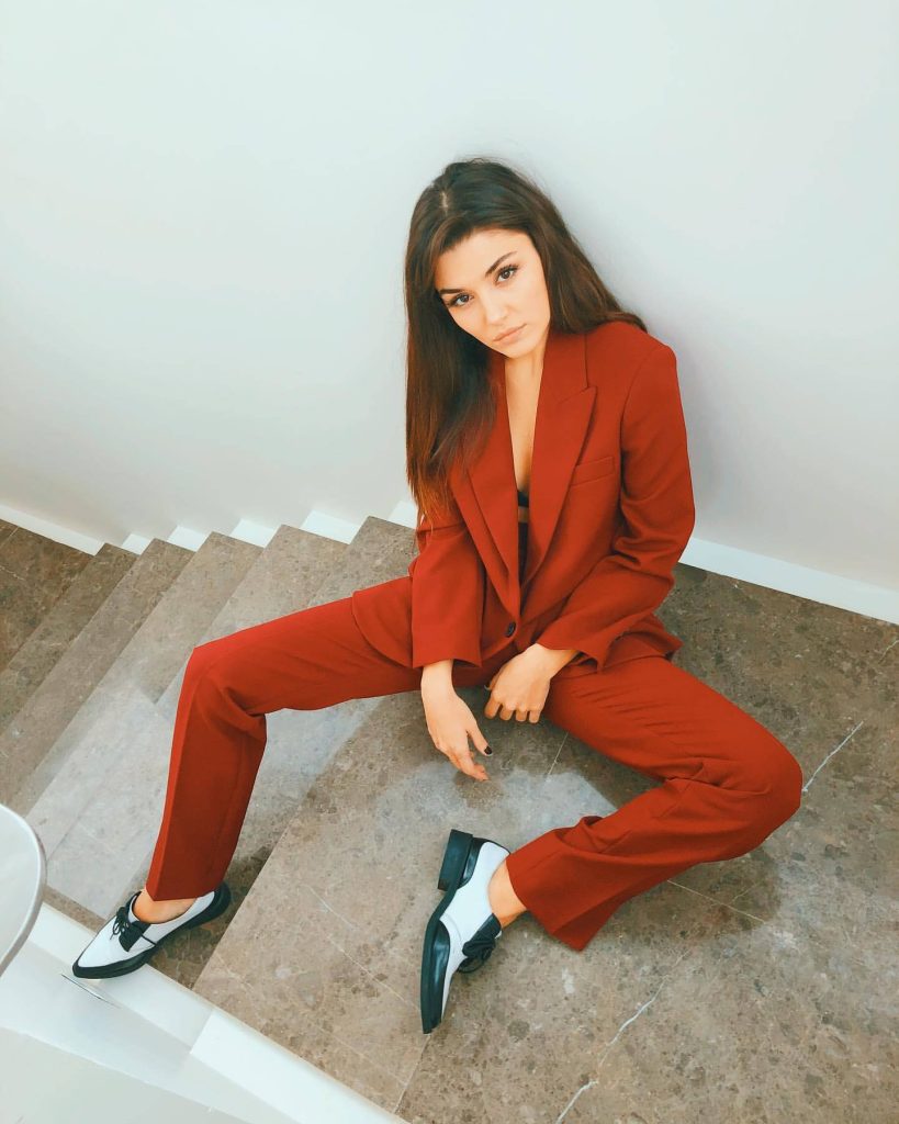 Hande Erçel in tailored red pantsuit posing on staircase stylish chic fashion portrait wallpaper