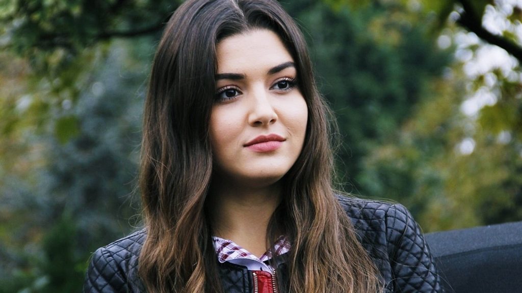 Portrait of Turkish actress Hande Erçel in black leather jacket in serene green park background Wallpaper