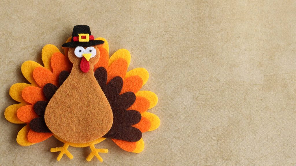 Festive handmade felt turkey Thanksgiving wallpaper warm autumn colors pilgrim hat textured background