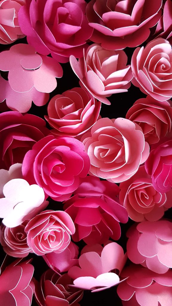 Close up of handmade paper roses in pink shades layered for romantic floral wallpaper background