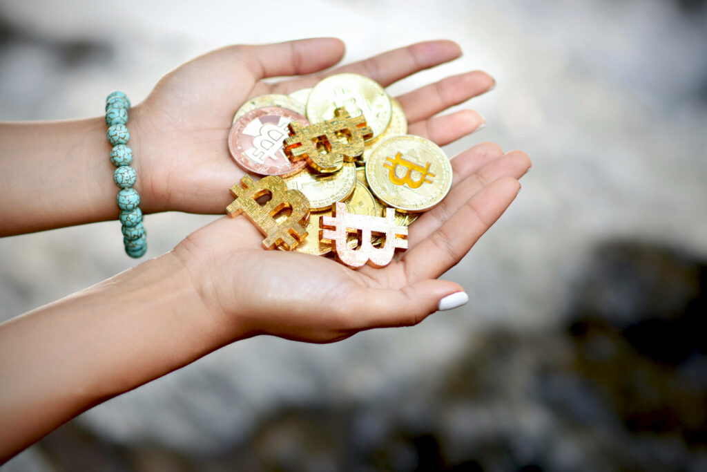 Hands holding multiple golden Bitcoin coins and symbols illustrating digital cryptocurrency concept Wallpaper