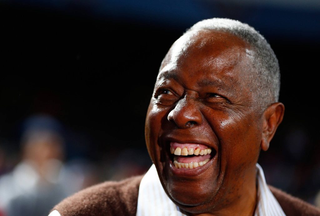 Close-up portrait of baseball legend Hank Aaron smiling warmly with dramatic lighting background Wallpaper
