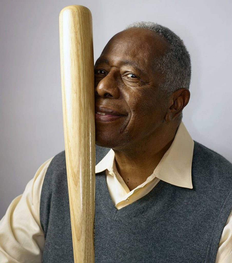 Hank Aaron portrait smiling resting cheek on wooden bat warm nostalgic lighting wallpaper