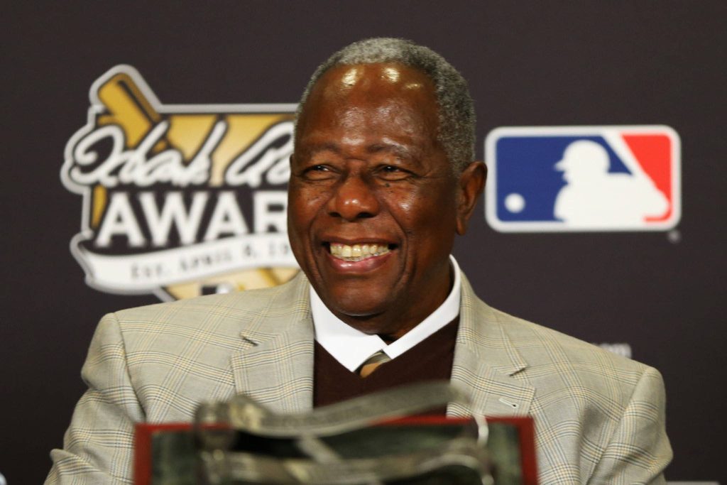 Hank Aaron smiling at MLB event wearing plaid blazer with Hank Aaron Award backdrop Wallpaper