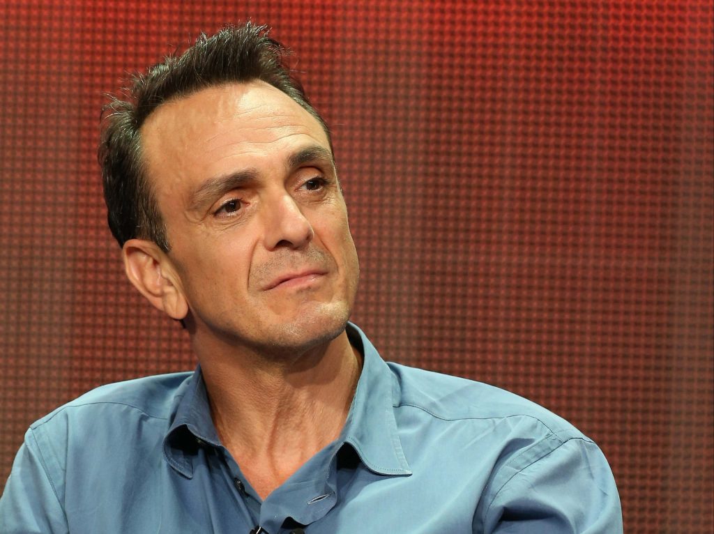 Portrait of American actor Hank Azaria in blue shirt with reddish-brown textured background wallpaper