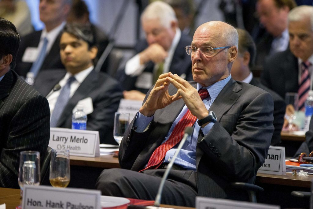 Hank Paulson in dark suit and red tie focused at formal corporate conference table meeting Wallpaper