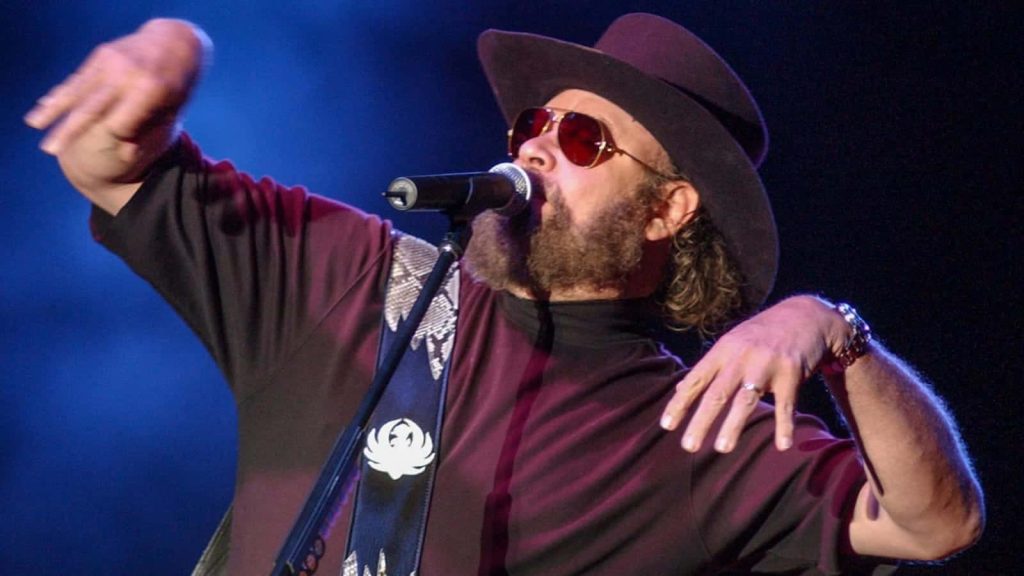 Hank Williams Jr performing live in cowboy hat and sunglasses on blue-lit concert stage wallpaper