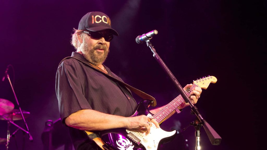Hank Williams Jr live concert vibrant purple stage electric guitar signature ICON cap sunglasses Wallpaper