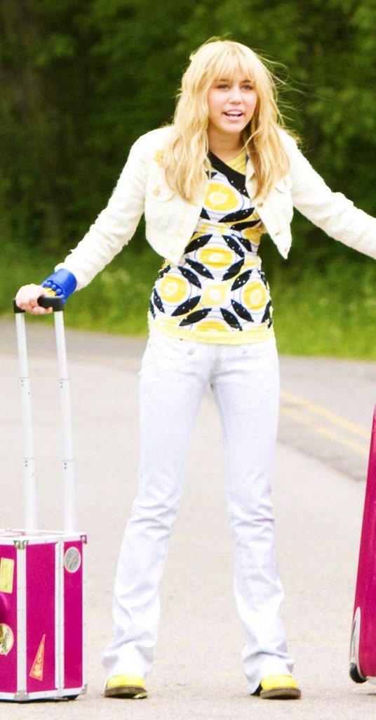 Hannah Montana Miley Cyrus in white jacket and jeans posing on rural path with luggage wallpaper