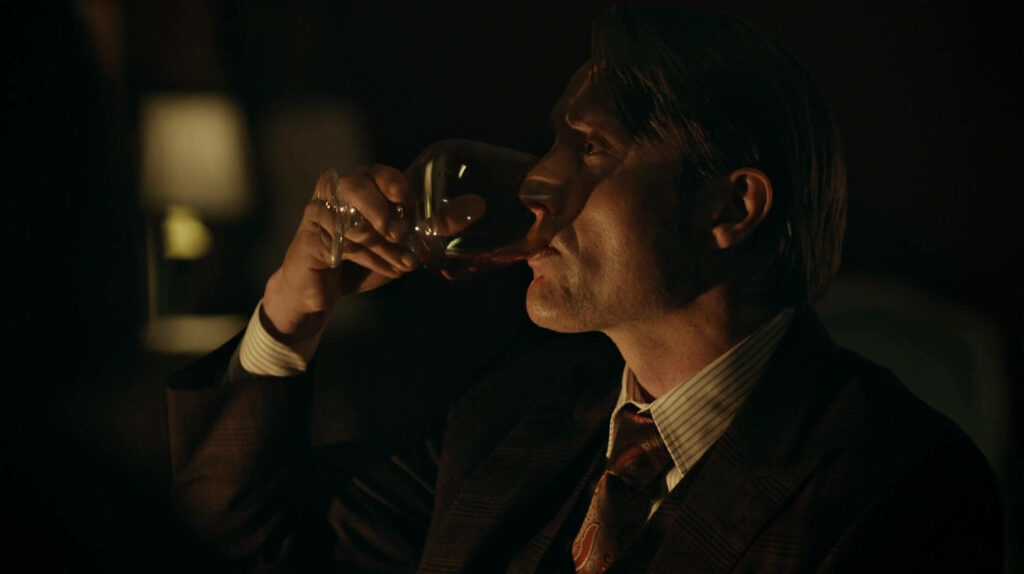 Hannibal Lecter Enjoys Wine: Elegant Dimly Lit Wallpaper Background