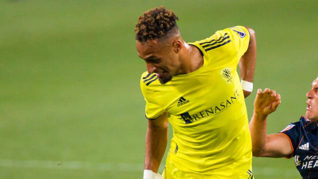 Hany Mukhtar in bright yellow Nashville SC jersey mid-match on green pitch MLS action wallpaper