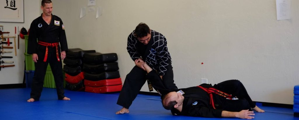 Hapkido martial arts power throw on blue mat with black doboks red belts instructor watching Wallpaper
