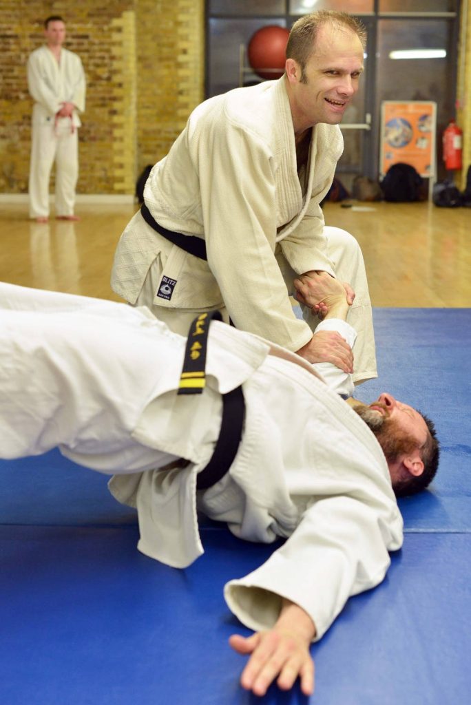 Hapkido wrist control martial arts demonstration in white gi bright dojo blue mat wallpaper
