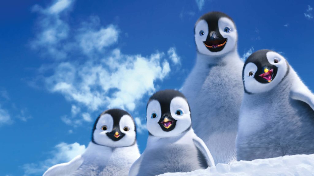 Happy Feet Two wallpaper with smiling baby penguins on snow under a bright blue sky background