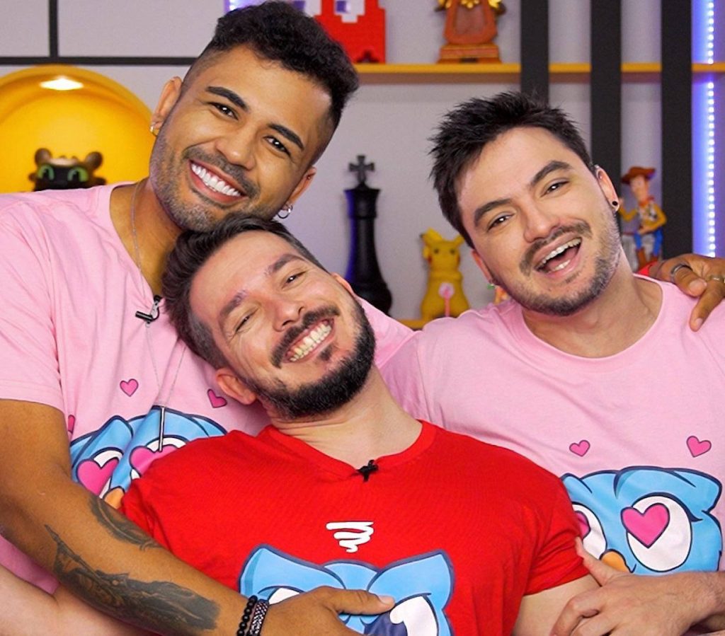 Happy Felipe Neto and friends smiling in vibrant studio wearing matching red pink t-shirts wallpaper
