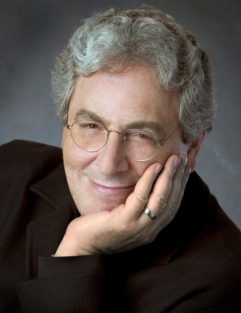 Portrait of filmmaker Harold Ramis in soft lighting wearing glasses and dark sweater on gray background Wallpaper