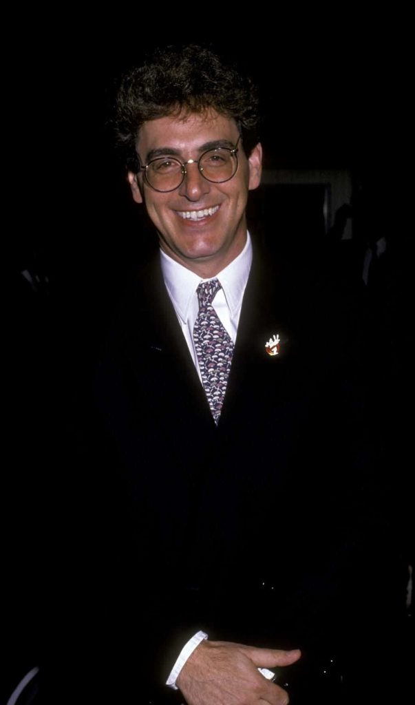 Portrait of Harold Ramis smiling in glasses dark suit with Ghostbusters pin high-quality photo Wallpaper