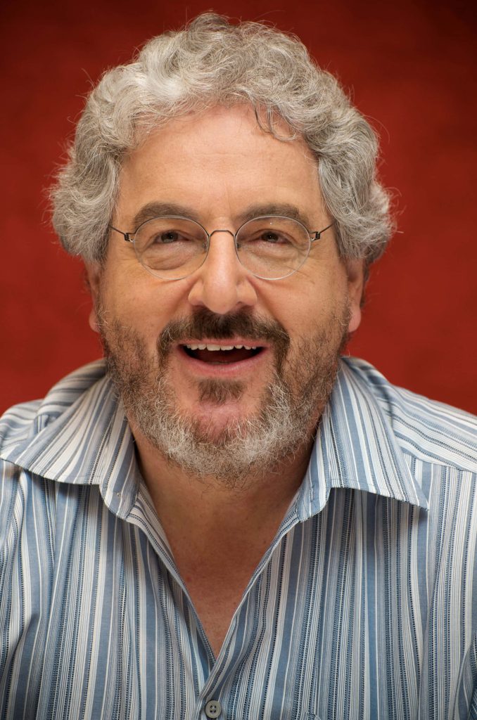 Harold Ramis portrait smiling with round glasses blue striped shirt red background wallpaper