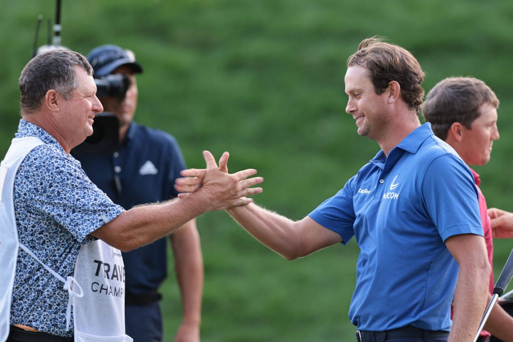 Professional golfer Harris English in blue polo high-fives caddie Eric Larson on green course Wallpaper