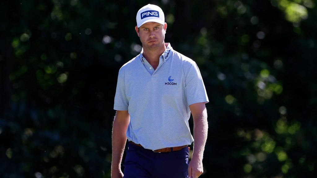 Harris English focused golf portrait wearing light blue M3COM polo and white PING cap outdoors Wallpaper