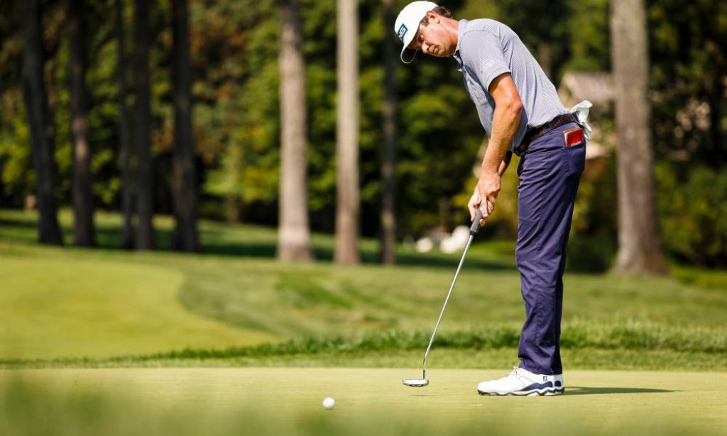 Pro golfer Harris English focused mid-putt on lush golf course wearing PING cap and blue polo Wallpaper