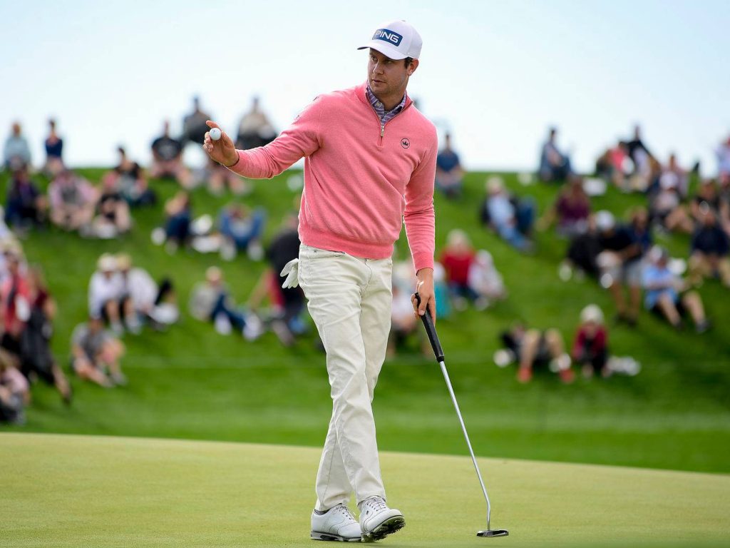 Golf pro Harris English in pink sweater preparing putt on green with blurred spectators background Wallpaper