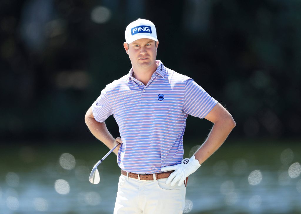 Harris English focused golf stance wearing PING cap striped polo white pants sunlit water background Wallpaper