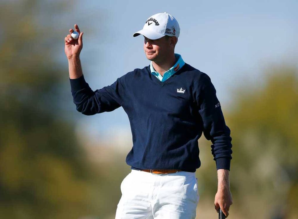Harris English on sunlit golf course holding ball in navy sweater white Callaway cap outdoors Wallpaper