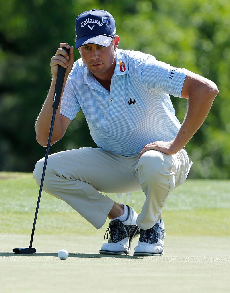 Harris English in blue polo reading putt on green with black putter golf wallpaper background
