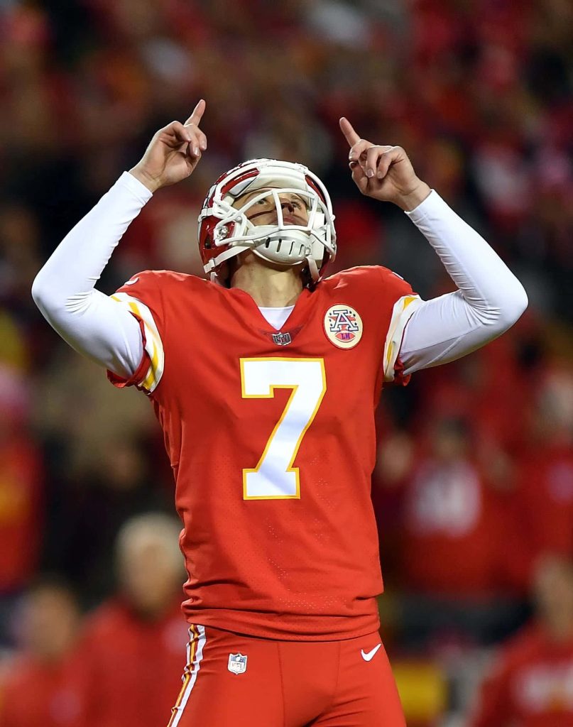 Kansas City Chiefs kicker Harrison Butker in red jersey celebrates field goal under stadium lights Wallpaper