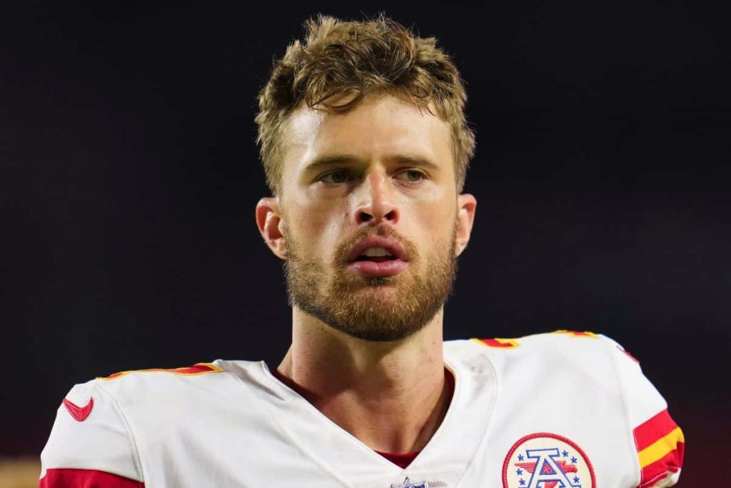 Harrison Butker NFL kicker in white Chiefs jersey intense focused portrait dark stadium background Wallpaper