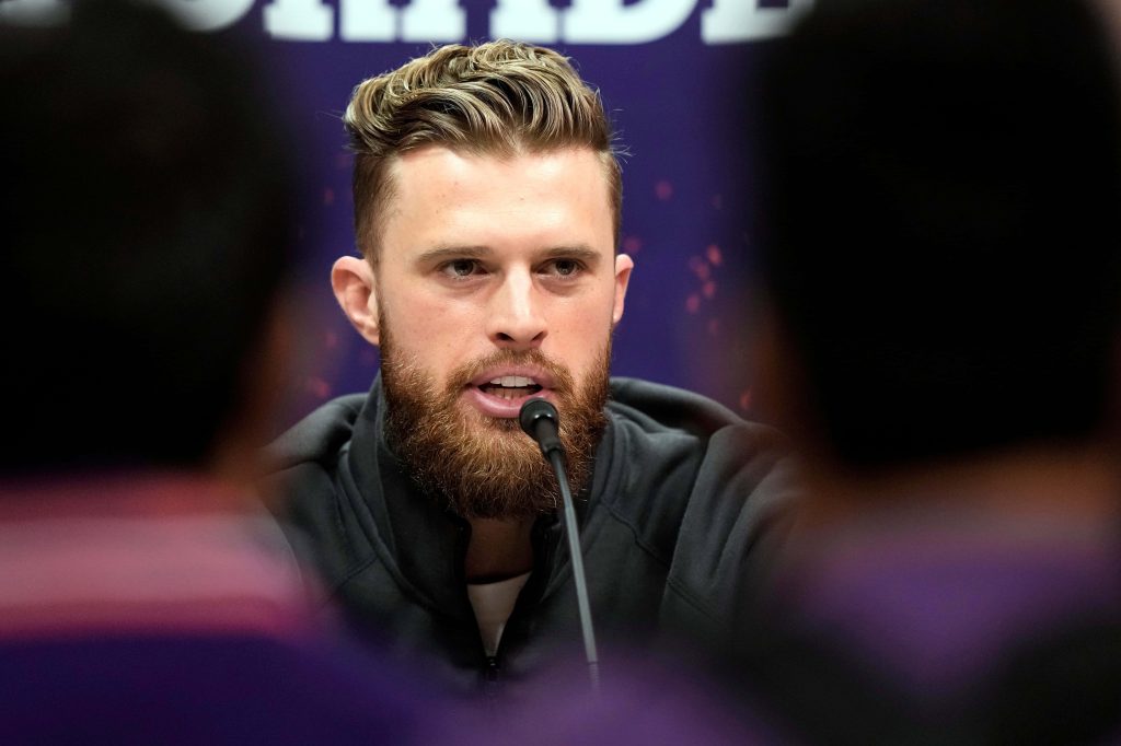 Close-up portrait of NFL kicker Harrison Butker in black jacket at press conference purple background Wallpaper