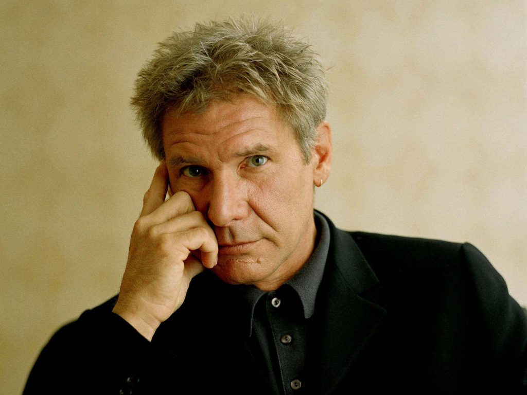 Harrison Ford portrait in black blazer with pensive expression soft lighting studio background Wallpaper