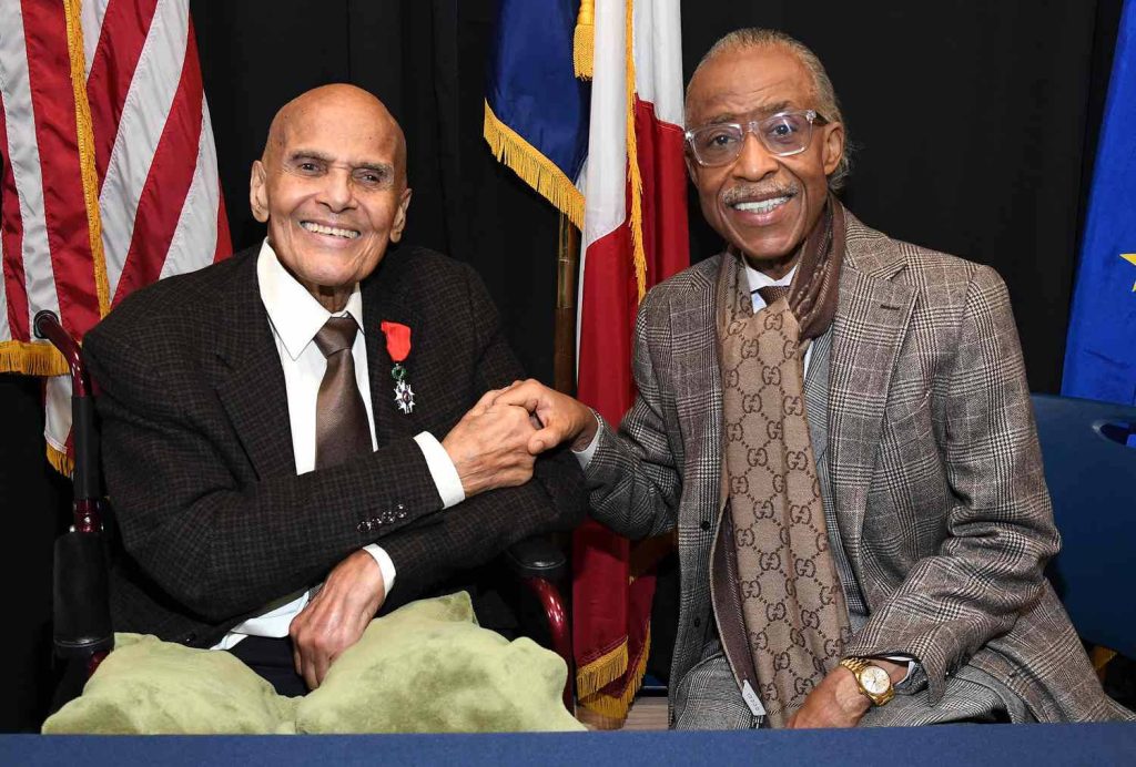 Harry Belafonte with Legion of Honour medal and Al Sharpton shaking hands smiling flags background Wallpaper