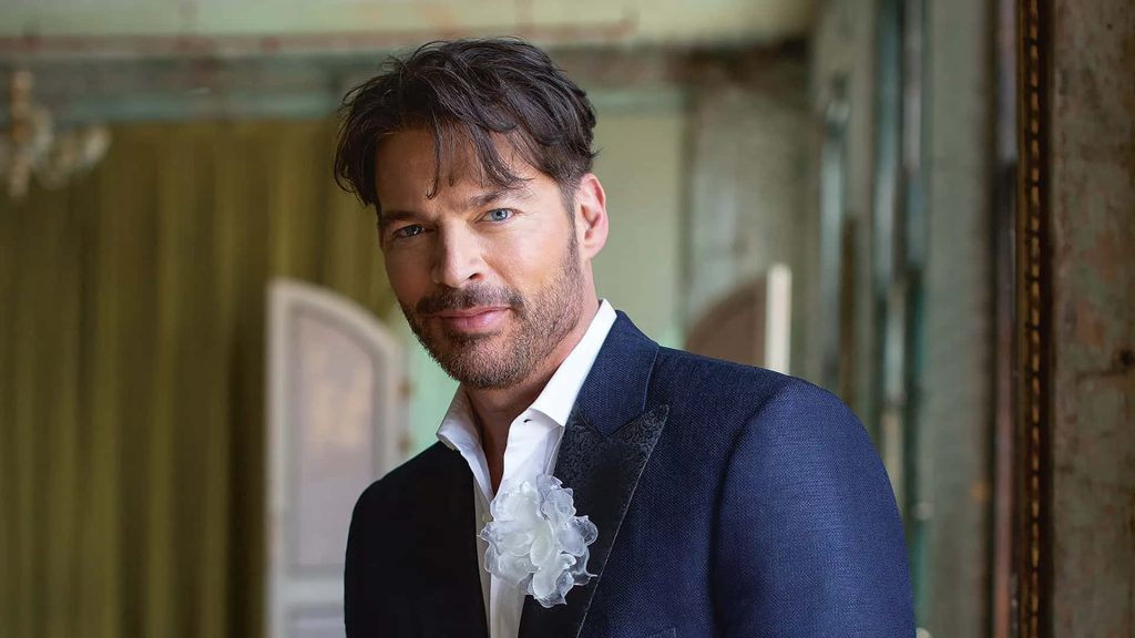 Harry Connick Jr. in navy blazer white shirt floral lapel pin rustic background natural light portrait Wallpaper