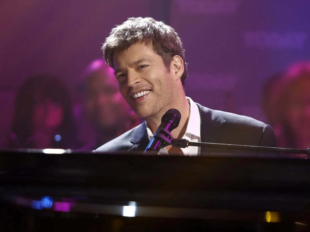 Harry Connick Jr singing and playing piano in purple lit studio sharp dark suit wallpaper background