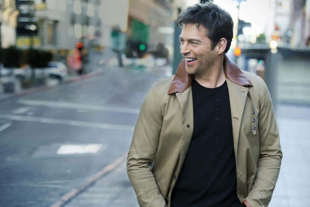 Harry Connick Jr smiling walking urban street wearing tan jacket black shirt bright natural light Wallpaper