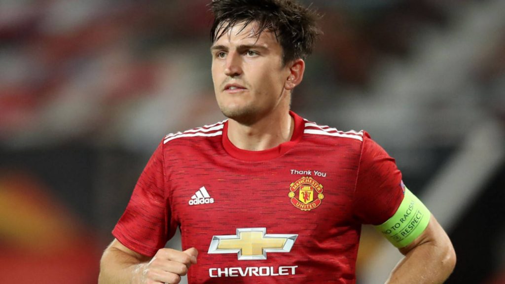 Harry Maguire in Manchester United red kit running on pitch intense sports wallpaper background