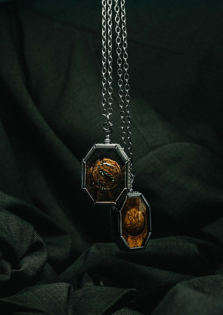 Harry Potter Horcrux wallpaper with Salazar Slytherin locket on dark moody fabric background