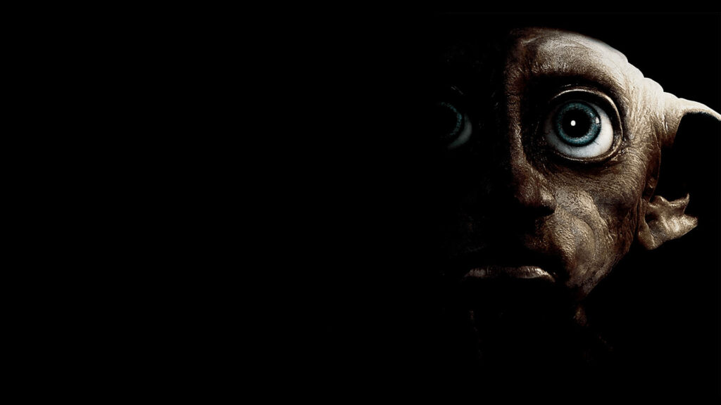 Freedom at Last: A Close-up of Harry Potter's Friend and House Elf Dobby with a Shadowed Face in Wallpaper Background